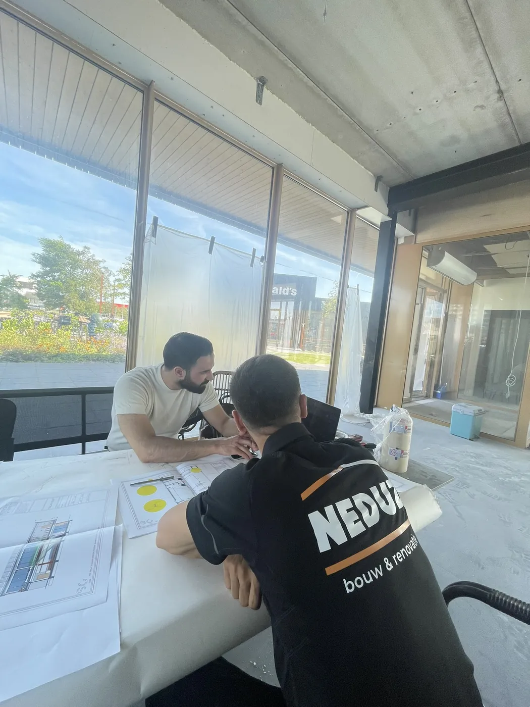 Twee vakmensen van Neduz bespreken de werktekeningen op locatie